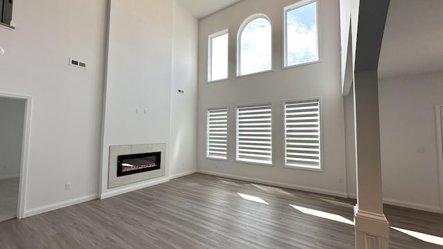 717 Angels Rest Way, Columbia, MO 65203 - unfurnished living room with a towering ceiling, wood finished floors, and a tiled fireplace