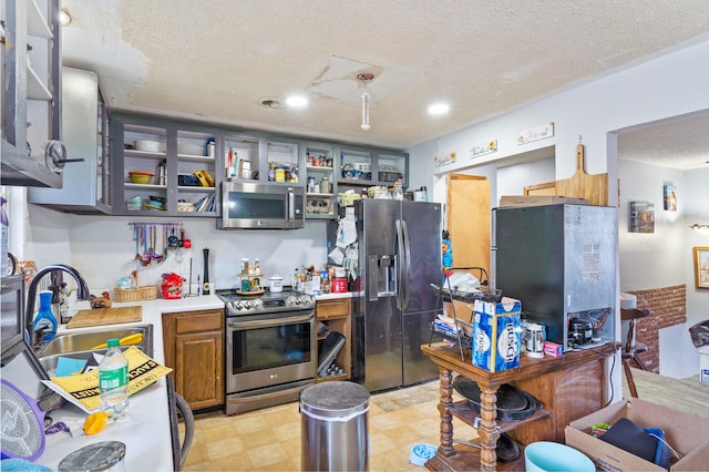 3601 W Hilltop Dr, Columbia, MO 65203 - kitchen featuring stainless steel appliances, light countertops, a textured ceiling, light floors, and brown cabinetry