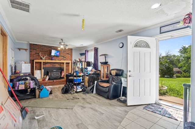 3601 W Hilltop Dr, Columbia, MO 65203 - living room featuring crown molding, a wood stove, a ceiling fan, a textured ceiling, and wood finished floors
