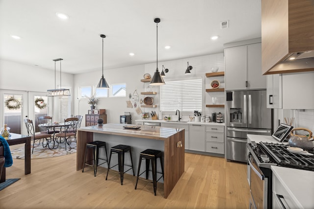 613 Red Feather Ct, Columbia, MO 65203 - kitchen featuring open shelves, appliances with stainless steel finishes, range hood, a breakfast bar area, and tasteful backsplash