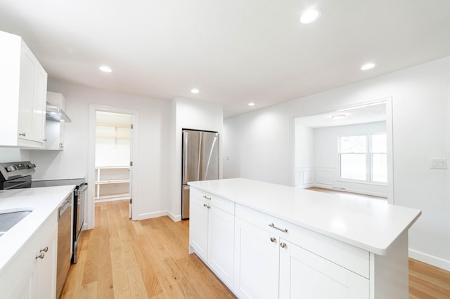 3112 Crestwood Ln, Columbia, MO 65203 - kitchen featuring appliances with stainless steel finishes, light wood-style flooring, light countertops, white cabinetry, and a center island