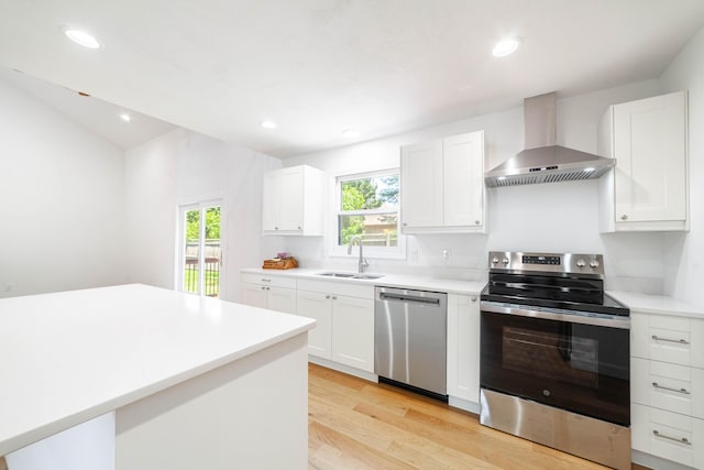 3112 Crestwood Ln, Columbia, MO 65203 - kitchen with appliances with stainless steel finishes, wall chimney range hood, light wood-style flooring, white cabinetry, and recessed lighting
