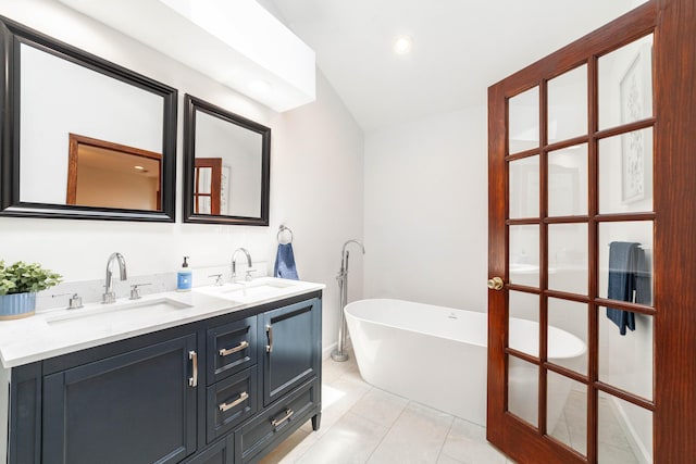 3112 Crestwood Ln, Columbia, MO 65203 - bathroom featuring a freestanding bath, double vanity, vaulted ceiling, tile patterned flooring, and recessed lighting