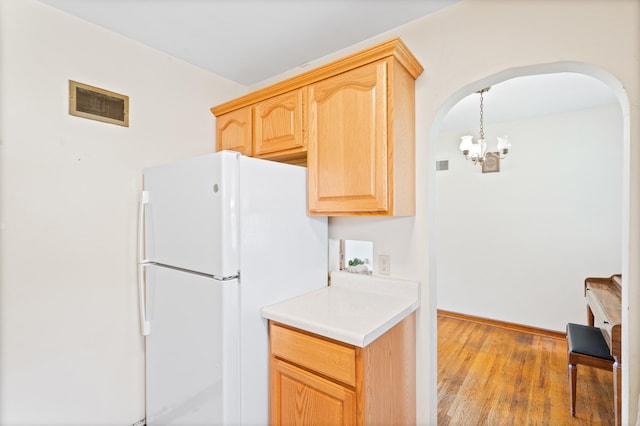 709 Clayton St, Columbia, MO 65203 - kitchen with freestanding refrigerator, arched walkways, light brown cabinetry, a chandelier, and wood finished floors
