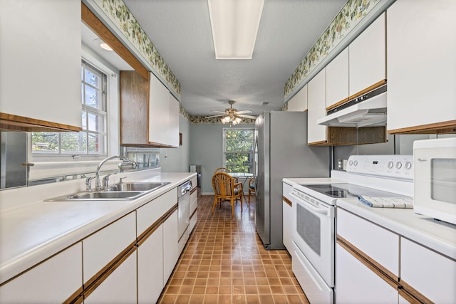 2710 Rollins Rd Unit A-1, Columbia, MO 65203 - kitchen featuring white appliances, under cabinet range hood, light countertops, white cabinetry, and a textured ceiling