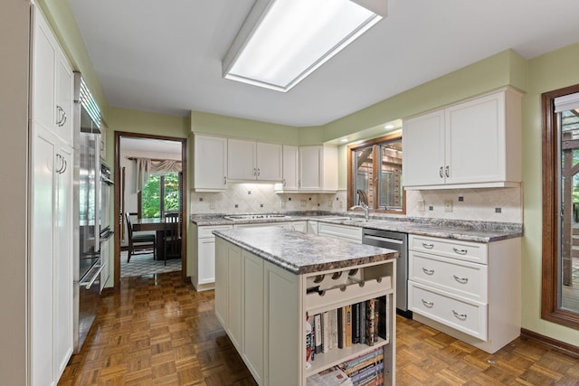 3707 Woodridge Ct, Columbia, MO 65201 - kitchen featuring stainless steel dishwasher, white cabinets, backsplash, and a center island