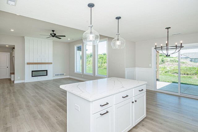 4512 Chambers Bay Dr, Columbia, MO 65201 - kitchen with a center island, light stone countertops, light wood finished floors, decorative light fixtures, and wainscoting