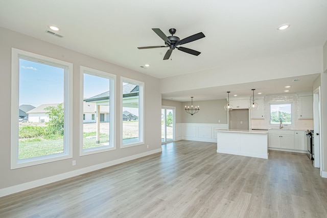 4512 Chambers Bay Dr, Columbia, MO 65201 - unfurnished living room with light wood finished floors, a chandelier, healthy amount of natural light, ceiling fan, and wainscoting