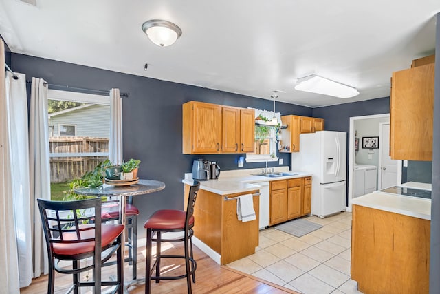 547 E Clearview Dr, Columbia, MO 65202 - kitchen featuring washing machine and dryer, white appliances, light countertops, light wood-type flooring, and a peninsula