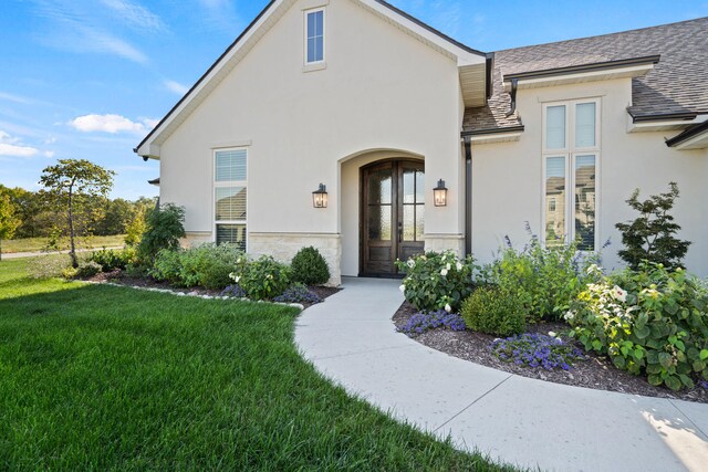 7405 Brackenhill Dr, Columbia, MO 65203 - view of exterior entry with stucco siding, a lawn, a shingled roof, and stone siding