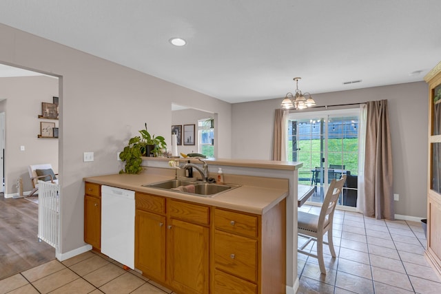 3810 Crocodile Dr, Columbia, MO 65202 - kitchen with white dishwasher, a peninsula, light countertops, a chandelier, and light tile patterned floors