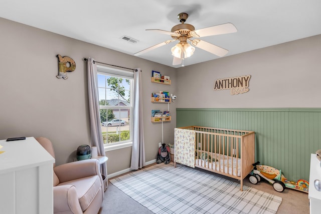 3810 Crocodile Dr, Columbia, MO 65202 - carpeted bedroom with a crib, a wainscoted wall, and a ceiling fan
