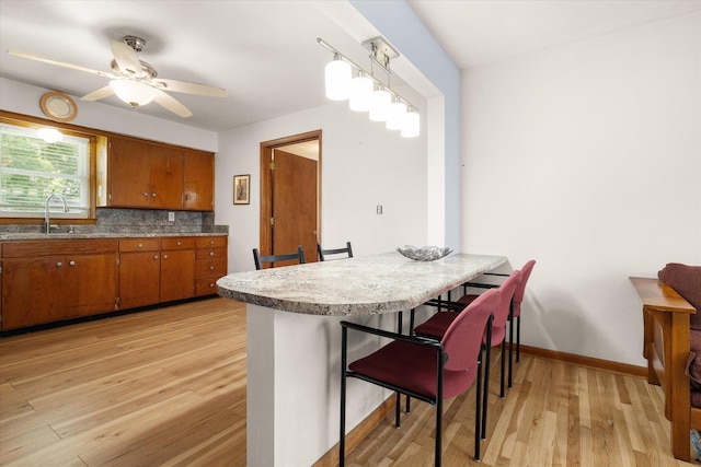 201 Ruby Ln, Columbia, MO 65203 - kitchen featuring brown cabinetry, light wood finished floors, a ceiling fan, a breakfast bar, and light countertops