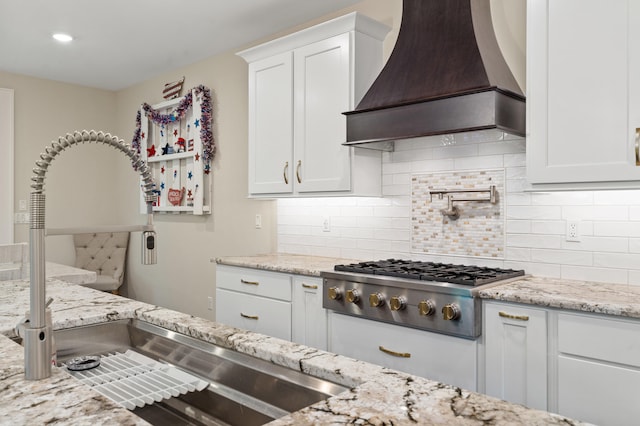 1880 W Cresskill Dr, Columbia, MO 65203 - kitchen with premium range hood, stainless steel gas cooktop, white cabinets, light stone countertops, and tasteful backsplash