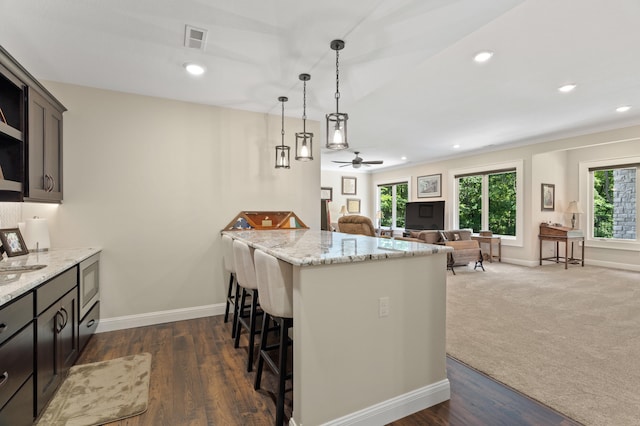 1880 W Cresskill Dr, Columbia, MO 65203 - kitchen featuring a breakfast bar, a peninsula, pendant lighting, light stone counters, and a ceiling fan