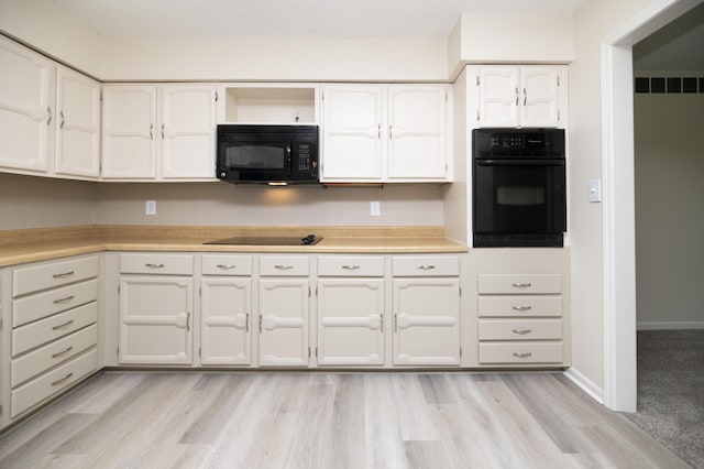 6303 S Old Village Rd, Columbia, MO 65203 - kitchen with black appliances, light wood-style flooring, white cabinetry, and light countertops
