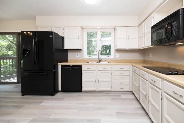 6303 S Old Village Rd, Columbia, MO 65203 - kitchen featuring black appliances, white cabinets, light countertops, and light wood-style floors