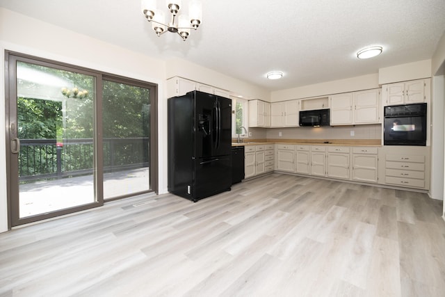 6303 S Old Village Rd, Columbia, MO 65203 - kitchen featuring black appliances, healthy amount of natural light, a chandelier, light wood-style flooring, and a textured ceiling