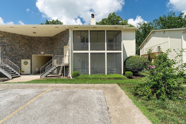 706 Park Deville Pl, Columbia, MO 65203 - back of house with a chimney, uncovered parking, stairway, and a sunroom