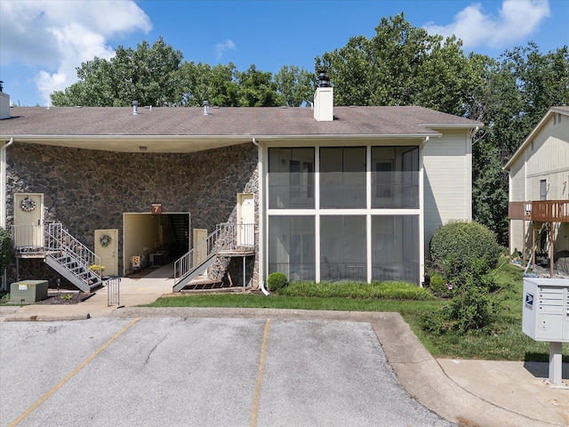 706 Park Deville Pl, Columbia, MO 65203 - back of house featuring a chimney, uncovered parking, a sunroom, stone siding, and stairs