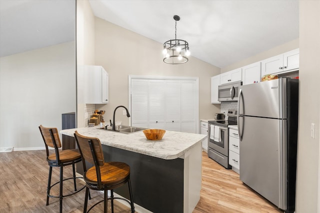 706 Park Deville Pl, Columbia, MO 65203 - kitchen featuring appliances with stainless steel finishes, vaulted ceiling, a breakfast bar, a peninsula, and white cabinets