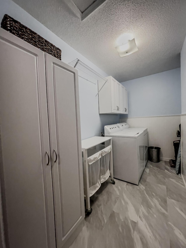 11657 Fletcher Ln, Holts Summit, MO 65043 - washroom with cabinet space, washer and dryer, a textured ceiling, and light marble finish flooring