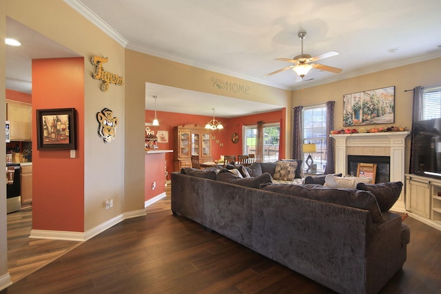 5805 Vero Way, Columbia, MO 65201 - living room featuring dark wood-style floors, a ceiling fan, a tiled fireplace, ornamental molding, and a chandelier