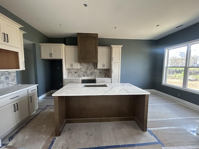 913 Spyglass Ct, Columbia, MO 65201 - kitchen featuring a center island, backsplash, custom range hood, and light stone countertops