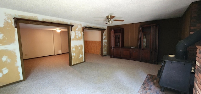 2716 Shagbark Cir, Jefferson City, MO 65109 - unfurnished living room featuring a wood stove, ceiling fan, a textured ceiling, and light carpet