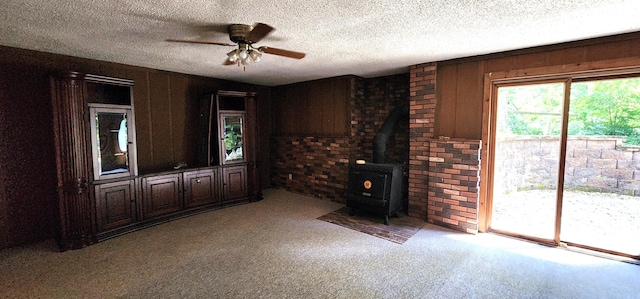 2716 Shagbark Cir, Jefferson City, MO 65109 - unfurnished living room with carpet flooring, a wood stove, brick wall, a textured ceiling, and a ceiling fan