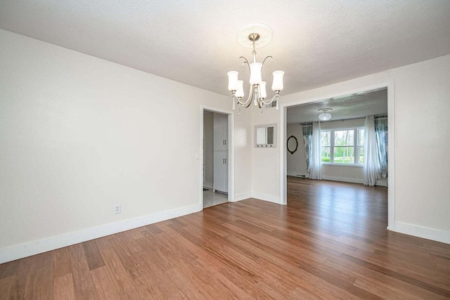 2130 E 163, Columbia, MO 65201 - spare room with a chandelier, wood finished floors, and a textured ceiling