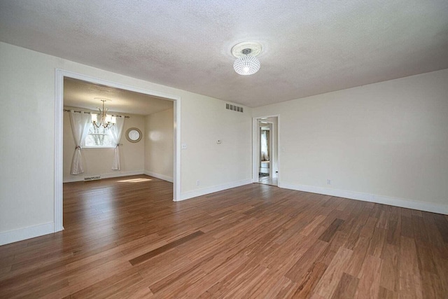 2130 E 163, Columbia, MO 65201 - empty room with a chandelier, wood finished floors, and a textured ceiling