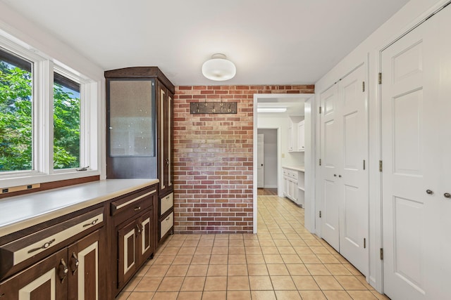 450 W Covered Bridge Rd, Columbia, MO 65203 - kitchen with light tile patterned floors, brick wall, light countertops, and dark brown cabinetry