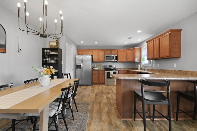 925 Kelli Ct, Centralia, MO 65240 - kitchen featuring stainless steel appliances, a chandelier, a peninsula, wood finished floors, and recessed lighting