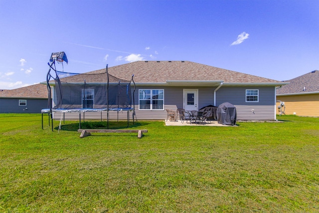 925 Kelli Ct, Centralia, MO 65240 - back of house with a trampoline, a patio, a lawn, and a shingled roof