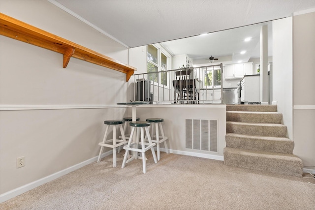 133 Manview Ln, Holts Summit, MO 65043 - kitchen featuring carpet flooring, a ceiling fan, a breakfast bar area, and white cabinets