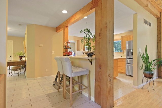 4241 E Ketterer Rd, Columbia, MO 65202 - kitchen with beamed ceiling, light brown cabinets, a kitchen breakfast bar, stainless steel fridge with ice dispenser, and light tile patterned floors