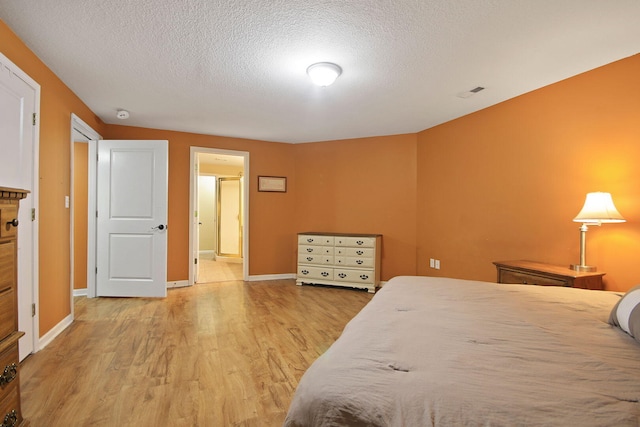 4241 E Ketterer Rd, Columbia, MO 65202 - bedroom with a textured ceiling, light wood-style floors, and ensuite bathroom