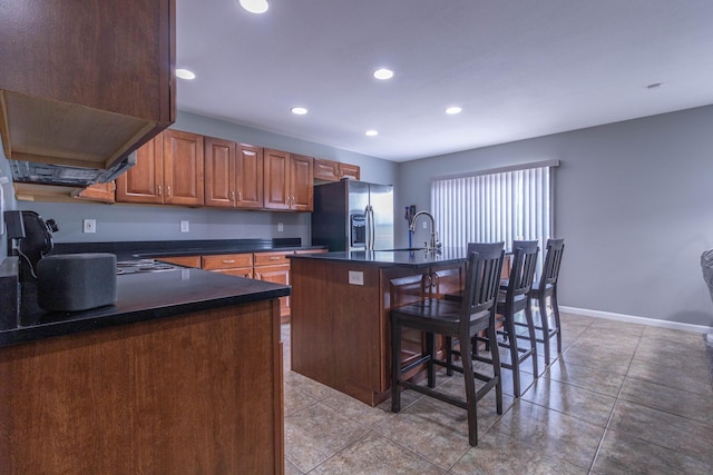 7700 N Ballew Rd, Hallsville, MO 65255 - kitchen featuring stainless steel fridge, dark countertops, a kitchen breakfast bar, recessed lighting, and an island with sink
