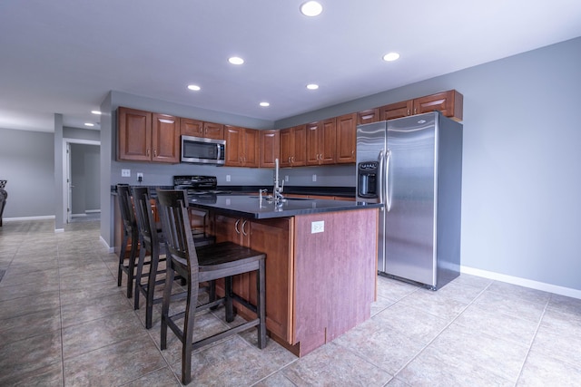 7700 N Ballew Rd, Hallsville, MO 65255 - kitchen with appliances with stainless steel finishes, dark countertops, recessed lighting, a kitchen island with sink, and a kitchen bar