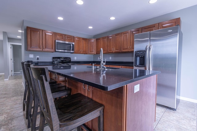 7700 N Ballew Rd, Hallsville, MO 65255 - kitchen with appliances with stainless steel finishes, dark countertops, recessed lighting, a center island with sink, and a kitchen breakfast bar
