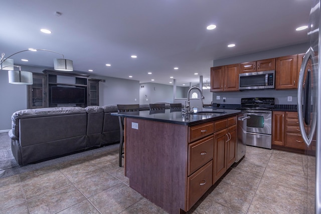 7700 N Ballew Rd, Hallsville, MO 65255 - kitchen with stainless steel appliances, dark countertops, a center island with sink, a breakfast bar area, and recessed lighting