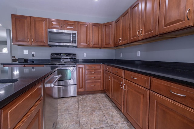 7700 N Ballew Rd, Hallsville, MO 65255 - kitchen featuring appliances with stainless steel finishes, brown cabinets, and dark stone countertops