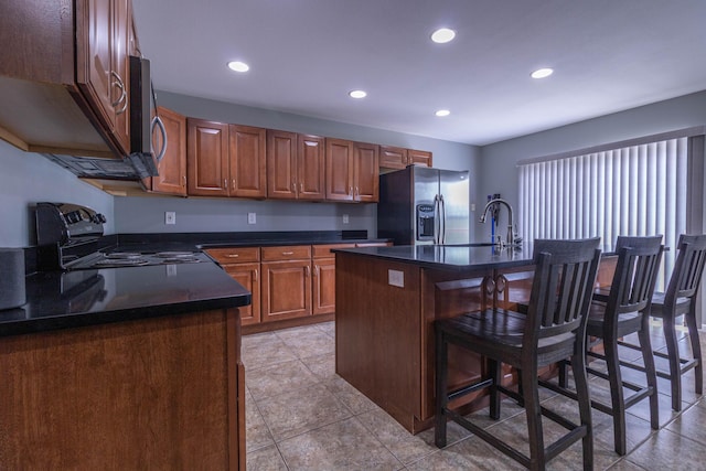 7700 N Ballew Rd, Hallsville, MO 65255 - kitchen with appliances with stainless steel finishes, dark countertops, a breakfast bar, recessed lighting, and brown cabinets