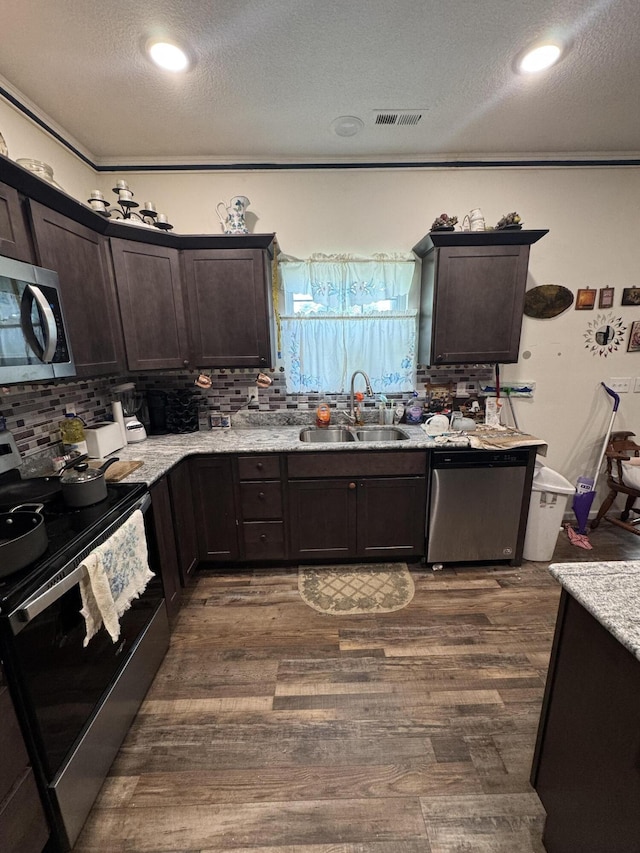 200 W Lakeview Ave, Centralia, MO 65240 - kitchen with appliances with stainless steel finishes, a textured ceiling, dark brown cabinetry, tasteful backsplash, and dark wood-type flooring
