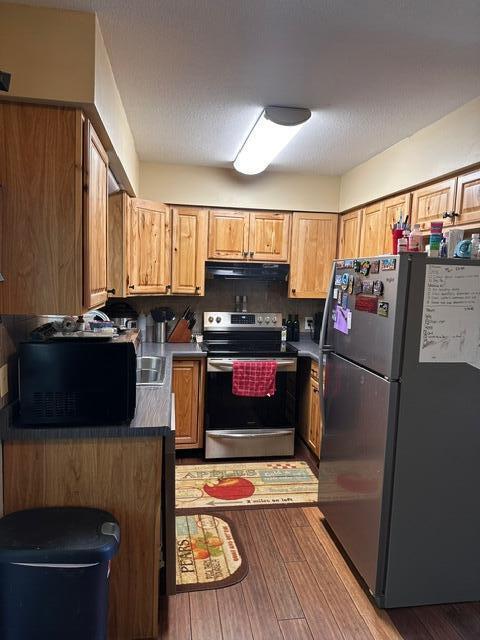 511 Turner Ave, Ashland, MO 65010 - kitchen with appliances with stainless steel finishes, light wood-style floors, dark countertops, ventilation hood, and brown cabinets