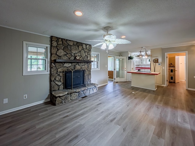 living area featuring a fireplace, wood finished floors, crown molding, and baseboards