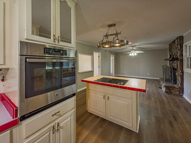 kitchen with dark wood-type flooring, tile counters, black electric stovetop, and stainless steel oven