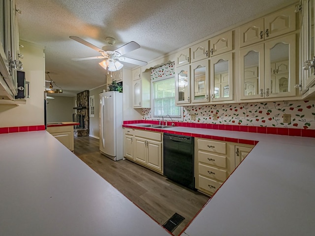 kitchen featuring cream cabinets, dishwasher, freestanding refrigerator, and wood finished floors