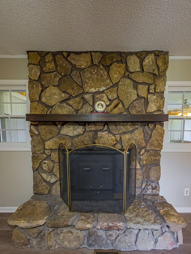 interior details featuring ornamental molding, a textured ceiling, wood finished floors, and baseboards